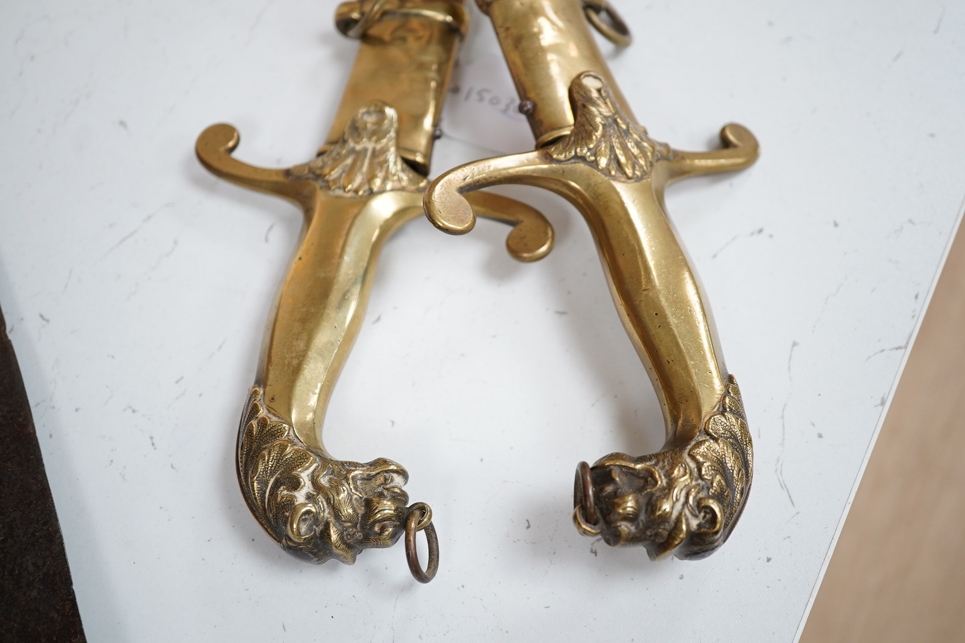 A pair of Victorian bandsman’s swords of Shamshir type, curved single edge blades, cast brass hilts with lions head pommels, in their brass scabbards. Condition - good, some dents to scabbards.